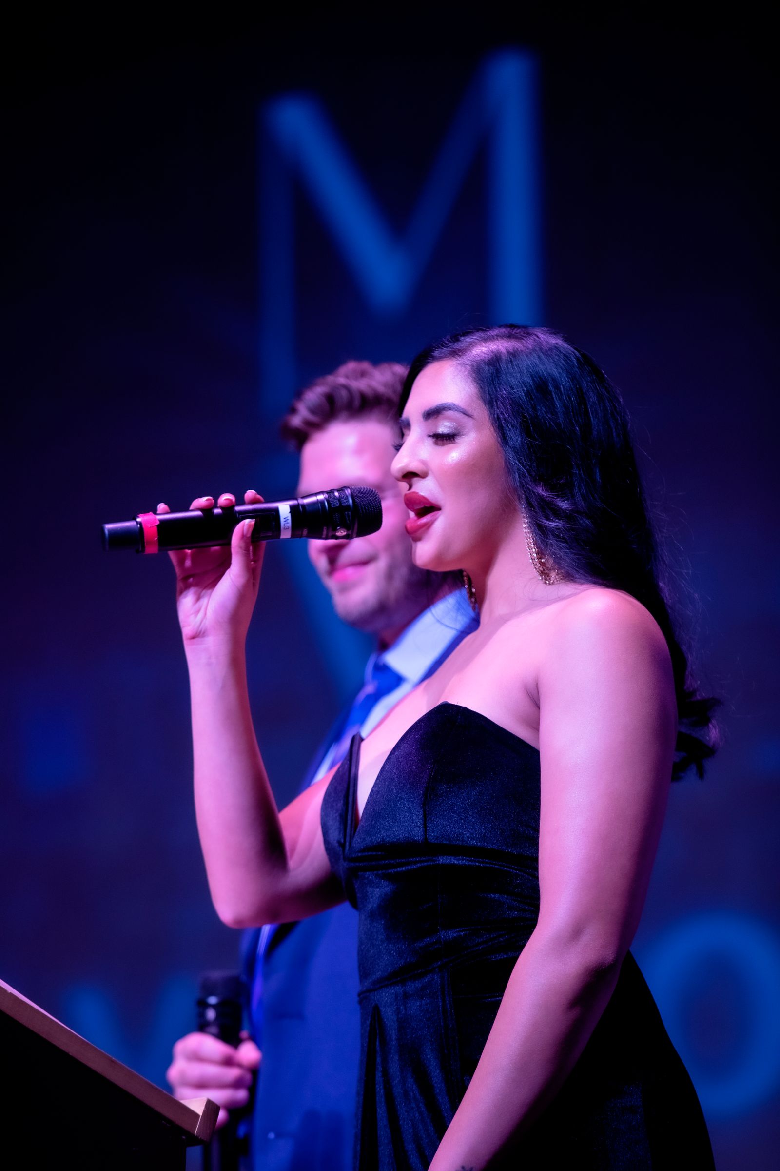 Singer performing live under blue and magenta stage lights