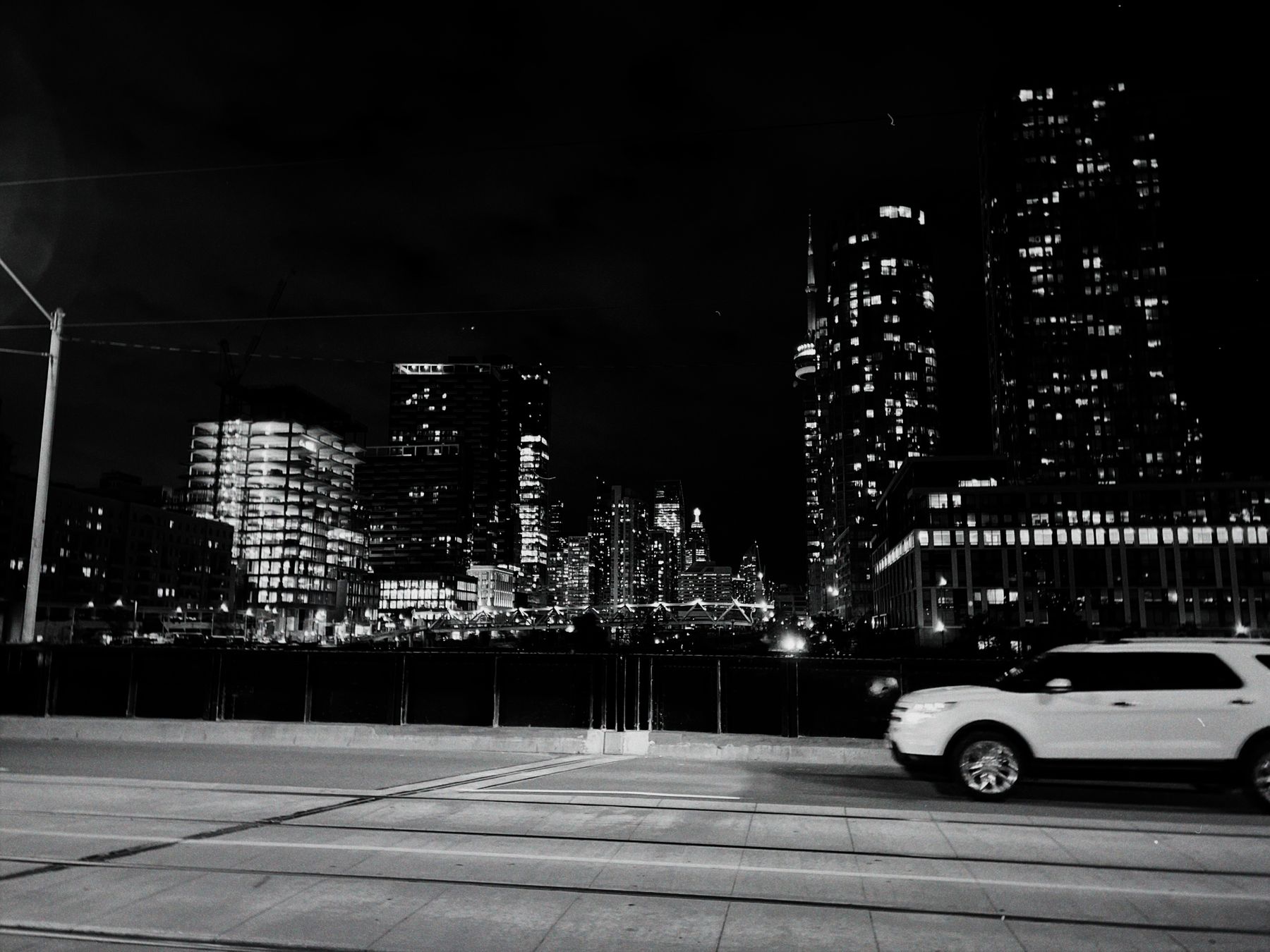 Black-and-white Toronto skyline and passing car photographed at night