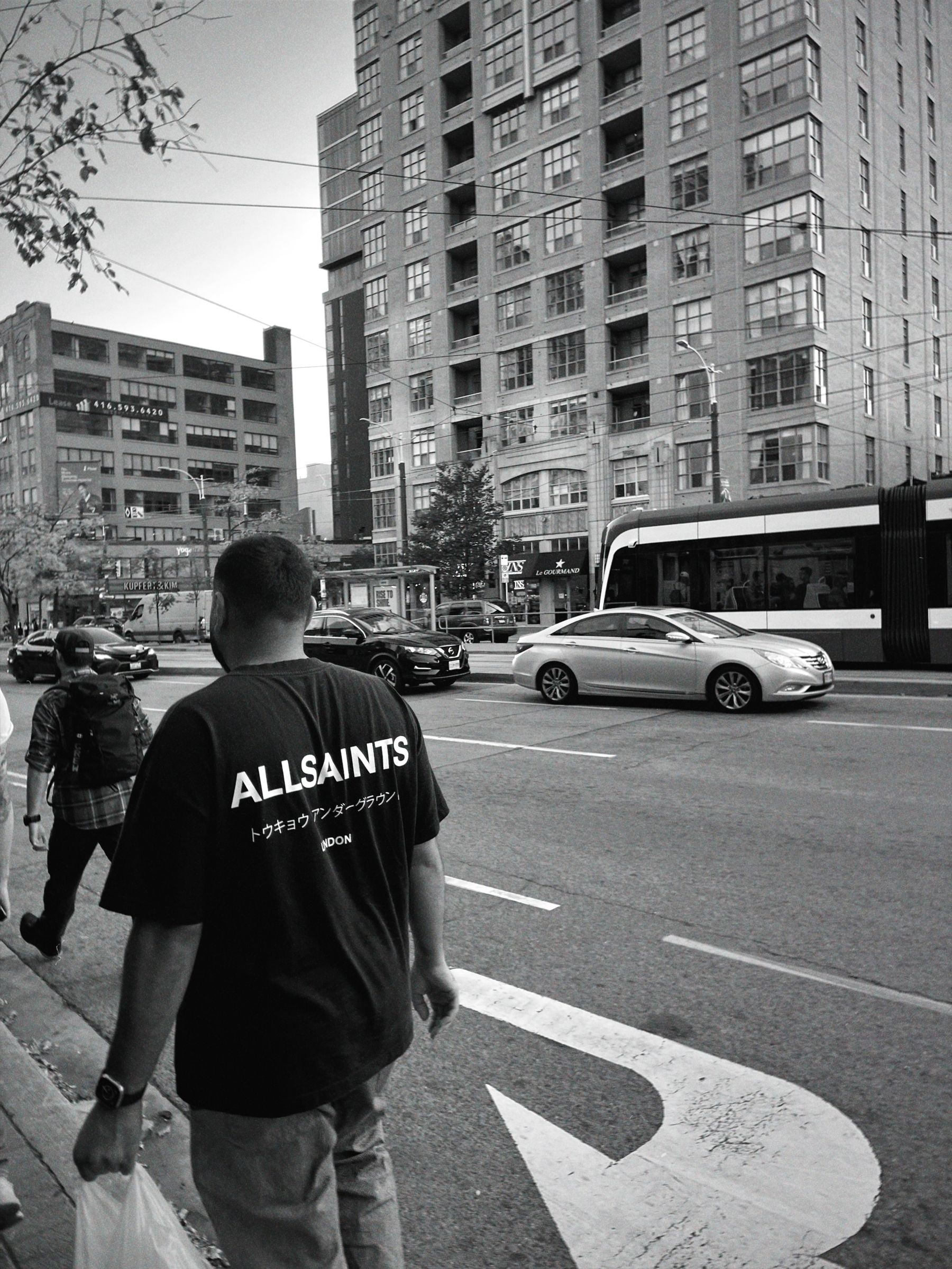 Black-and-white street portrait crossing a busy Toronto intersection
